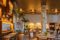 um restaurante com mesas e cadeiras de madeira e um balcão em Saluz Boutique Hotel em Jericoacoara