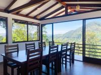 Un comedor con mesa y sillas y ventanas. en PEKOE VALLEY Huluganga, en Huluganga