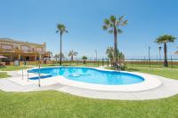 a pool with palm trees and a building at Apartamento Lance Playa in Tarifa