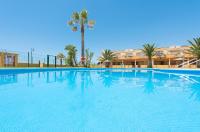a large swimming pool with palm trees and a building at Apartamento Lance Playa in Tarifa