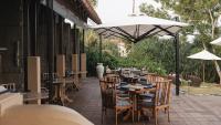Un patio al aire libre con mesas, sillas y una sombrilla. en Cape Weligama - Relais and Chateaux, en Weligama