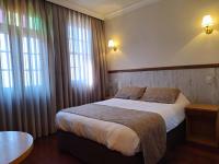 Un dormitorio con una cama grande y dos ventanas. en Boroni Palace Hotel, en Ouro Preto
