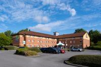 Un gran edificio de ladrillos con coches aparcados en un estacionamiento. en Holiday Inn Express Taunton East by IHG, en Taunton