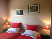 2 Betten in einem Zimmer mit roten und weißen Kissen in der Unterkunft Le Mas de Lucas in Arles