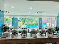 Un comedor con mesa y sillas y ventanas. en KANN Pattaya Hotel, en Pattaya South