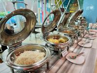 una fila de tazones metálicos de comida sobre una mesa en KANN Pattaya Hotel, en Pattaya South