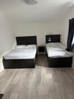Dos camas en una habitación con suelo de madera. en Sahota B&amp;B, en Rotherham