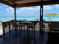a wooden deck with a table and chairs on the beach at Te Manu Lodge Tikehau in Tikehau