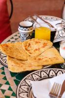 a table with a plate of naan bread and glasses of orange juice at Riad Mazouz102 Médina in Marrakech