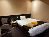 una habitación de hotel con una cama y una silla en Tabist Hirosaki Touei Hotel, en Hirosaki