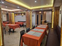 uma sala de jantar com mesas e cadeiras laranjas e um buscador de mesas em The Pinecrest em Gangtok