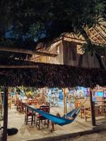a person in a blue hammock under a straw umbrella at daTerra Baucau agroecological farm stay in Deli
