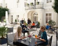people sitting at tables in the courtyard of a building at The Mozart Prague in Prague