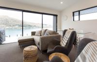 ein Wohnzimmer mit einem Sofa, Stühlen und Fenstern in der Unterkunft Highland Views in Queenstown