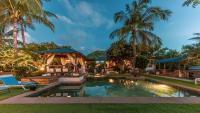 a resort pool with a gazebo and palm trees at Shanti Ghar Guest House in Tamarin