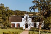 una vieja casa blanca con un árbol delante en Laborie Estate, en Paarl