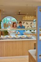 Um homem e uma mulher em pé em um balcão com pratos de comida. em PortoBay Blue Ocean em Albufeira