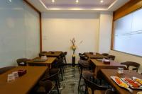 a dining room with tables and chairs and a large window at Hotel Sterling Executive in Navi Mumbai