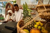 zwei Männer in einer Küche mit einem Obstkorb in der Unterkunft ZAN Orient Beach Hotel in Bwejuu