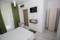 a white bedroom with a bed and a television at Hotel Atlantis in Eforie Nord