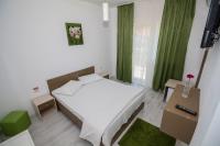 a small bedroom with a white bed and green curtains at Hotel Atlantis in Eforie Nord