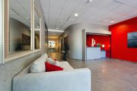 a living room with a white couch and a red wall at Ténéo Apparthotel Talence Arthena in Talence