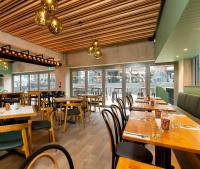 a restaurant with wooden tables and chairs and windows at Oaks Auckland Hotel in Auckland