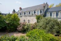 una vieja casa de piedra con arbustos delante de ella en Hôtel Diderot, en Chinon