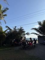 a group of people sitting at a picnic table near the beach at The Stables Oceanfront Hotel Midigama in Midigama