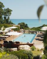 a swimming pool with chairs and umbrellas and the ocean at Casa Paradisu in LʼÎle-Rousse