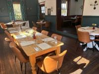 Un comedor con mesas y sillas de madera. en Rooms at the Inn, en Trotton