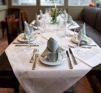 einen langen Tisch mit einem weißen Tischtuch und Besteck in der Unterkunft Appartementanlage am Arnumer See in Hemmingen