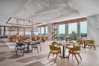 Un restaurante con mesas, sillas y ventanas. en voco Ma Belle Danang by IHG, en Da Nang