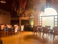 Un comedor con mesas y sillas y un gran ventanal. en Goa Country Club By Pearl I Luxury resort in Gurgaon, en Gurgaon