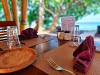 a wooden table with a fork and a plate of food at Nabuccos Spice Island Resort 
