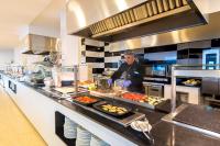 Un chef preparando comida en la cocina de un restaurante. en Cala Millor Garden Hotel - Adults Only, en Cala Millor