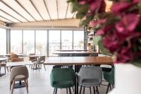 a dining room with tables and chairs and windows at Rise Urban Art Hotel in Larnaka