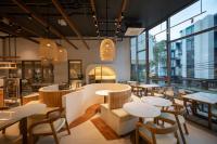 Un restaurante con mesas, sillas y ventanas. en The Moment, en Bangkok