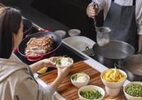 a woman is preparing food in a kitchen at OakValley Resort Hills Village in Wonju