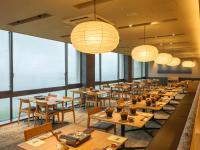 a restaurant with wooden tables and chairs and lights at KAMENOI HOTEL Oarai in Oarai