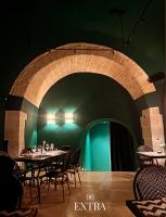 a dining room with tables and chairs and a green wall at Extra B&B in Trani