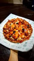 a pizza sitting on top of a plate on a table at Hotel The Pearl in Rourkela