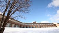 a building in the snow with a tree in the foreground at 富良野ホテル Furano Hotel in Furano