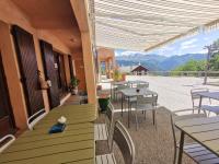 Un patio con mesas y sillas con montañas al fondo. en Auberge et Gites de Sauze, en Sauze