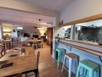 Un restaurante con mesas y sillas de madera y un bar. en Auberge et Gites de Sauze, en Sauze