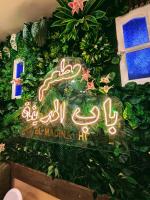 een uithangbord voor een hotel met planten en bloemen bij HOTEL Bab El Madina in Adrar