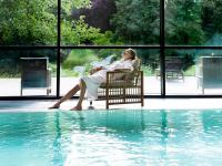 a woman sitting in a chair next to a swimming pool at Marienkron - Retreat &amp; Health Resort in Mönchhof