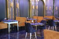 uma sala de jantar com mesas, cadeiras e lustres em Shedevr Plaza Navoiy em Navoi