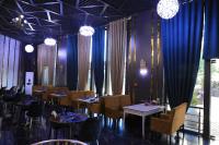 uma sala de jantar com mesas e cadeiras e cortinas azuis em Shedevr Plaza Navoiy em Navoi
