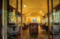 uma sala de jantar com mesas, cadeiras e janelas em The Crescent Wayanad Heritage Pool Resort em Sultan Bathery